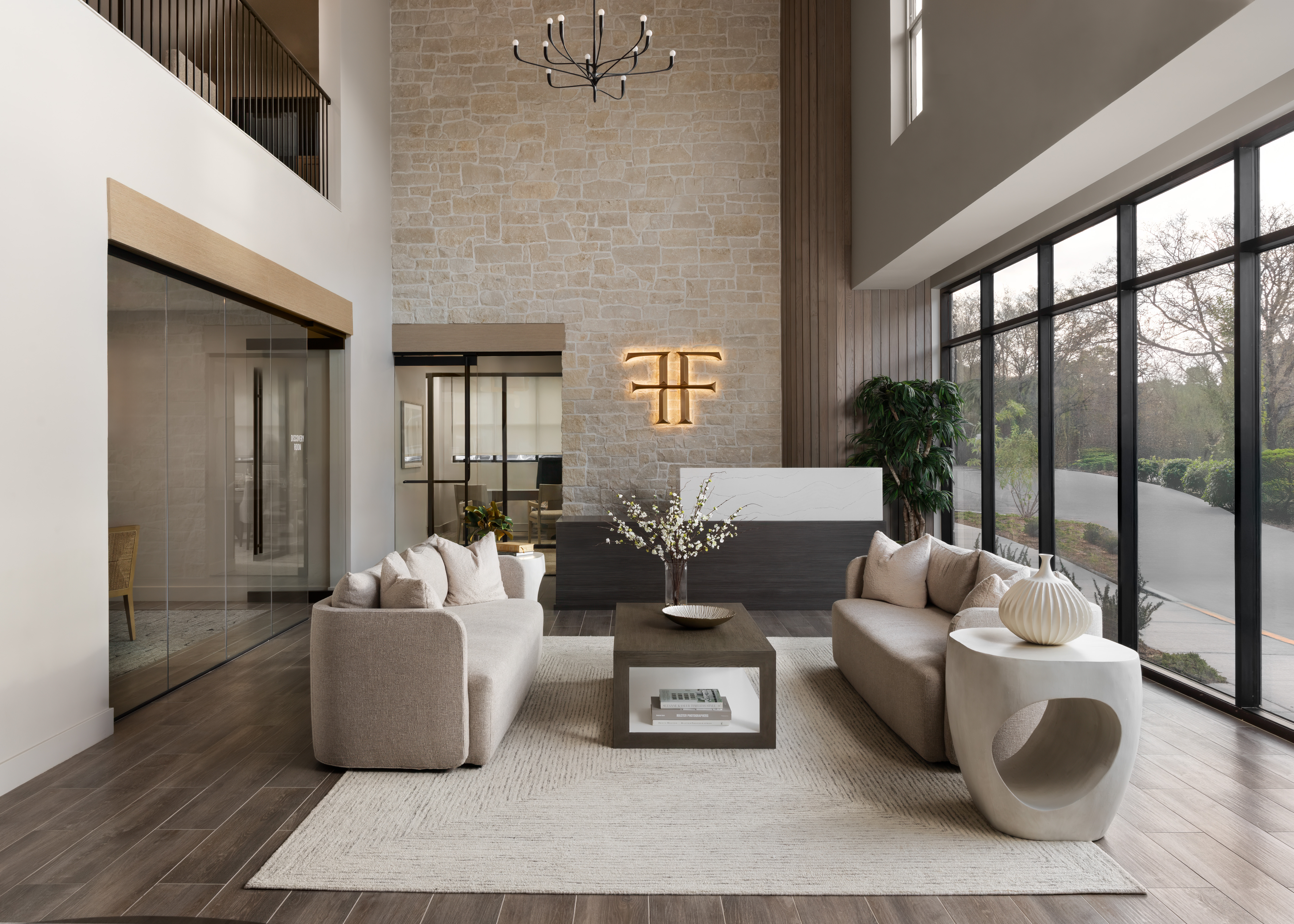 Luxury multifamily lobby featuring custom seating, stone feature wall, branded reception desk, and hospitality-inspired interior design for residential communities.