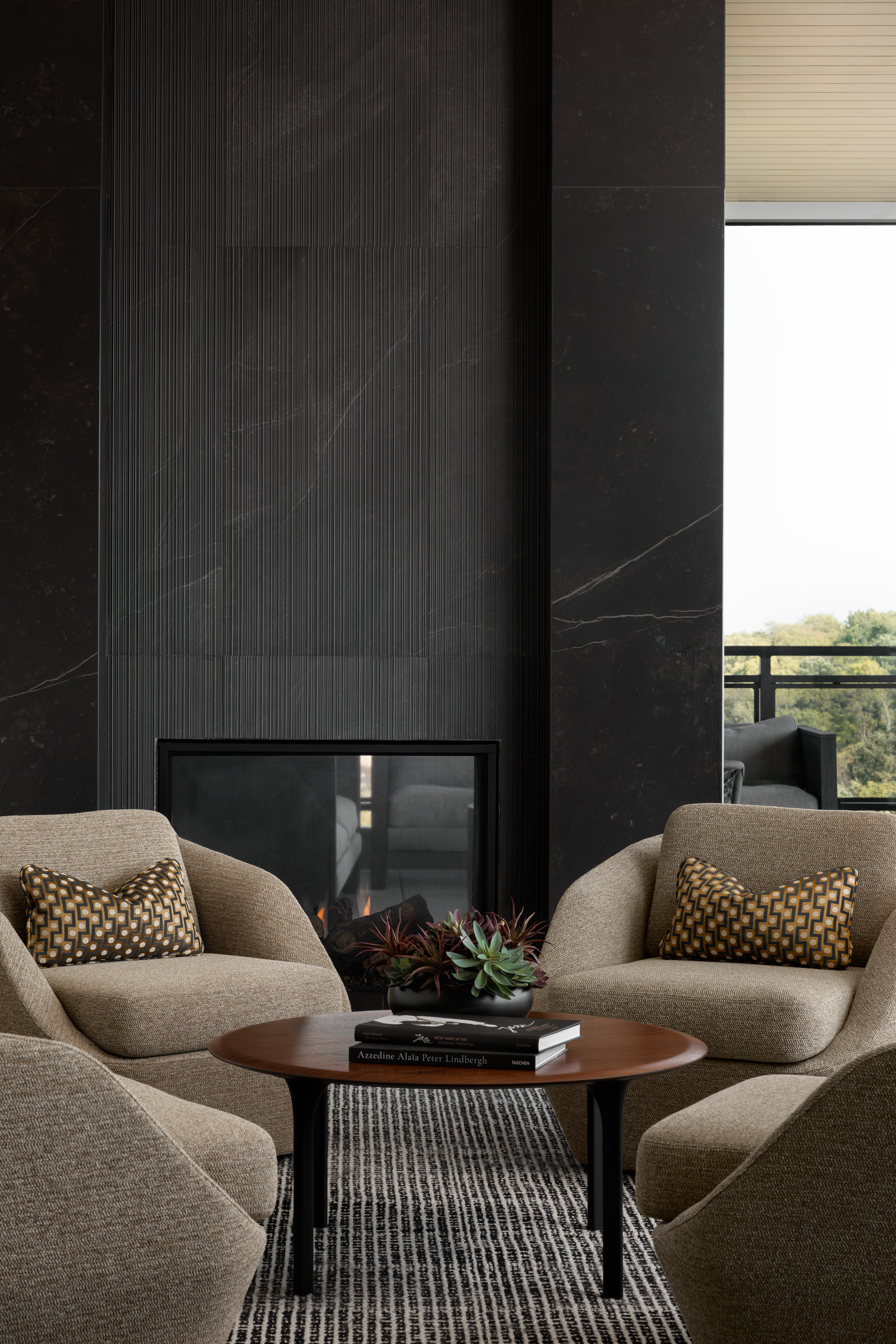 Luxury multifamily lounge with fireplace featuring durable upholstered lounge chairs, community seating arrangement, and hospitality-inspired interior design.