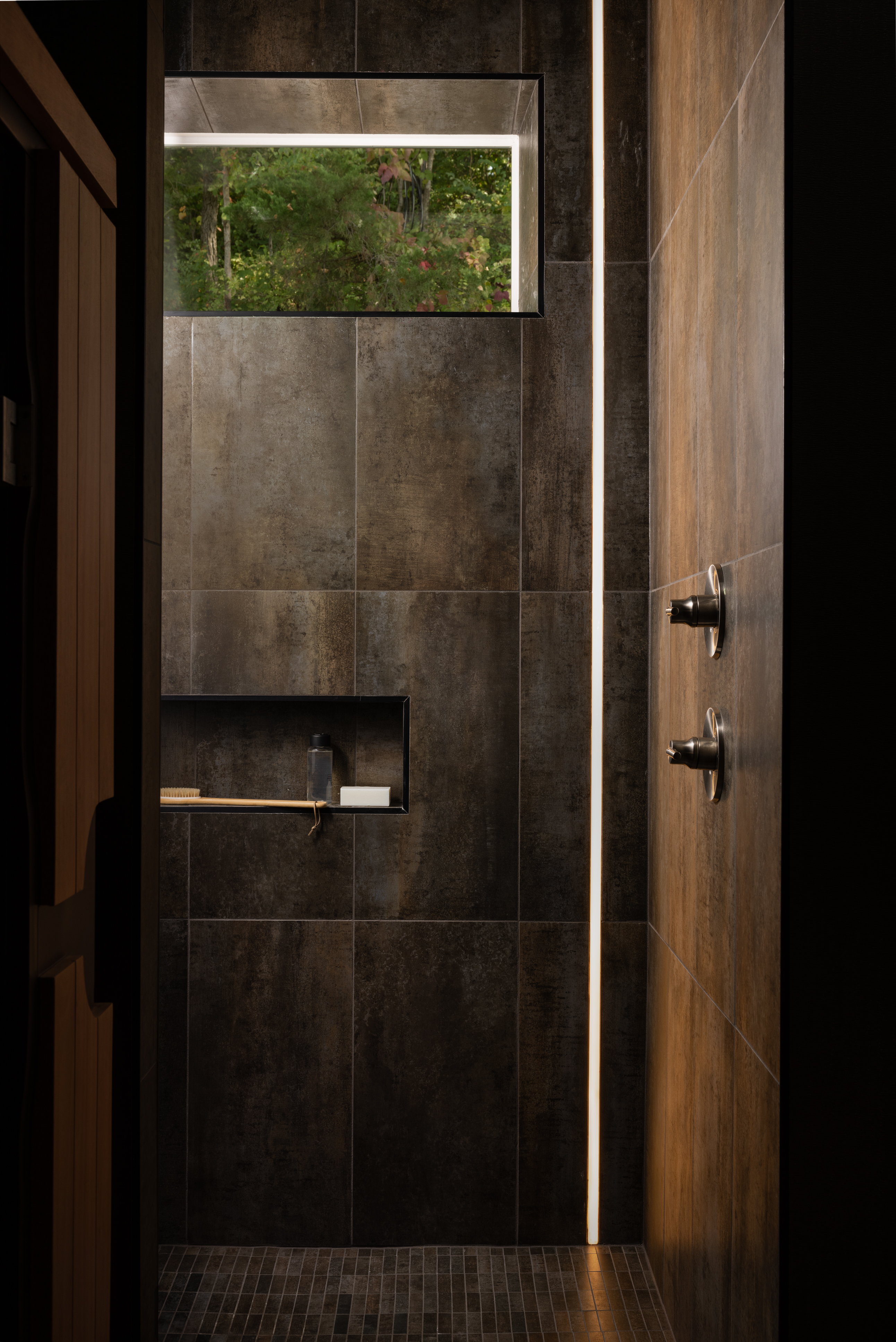 Luxury spa-style bathroom shower with large-format tile, integrated lighting, and modern fixtures designed for high-end residential and multifamily interiors.